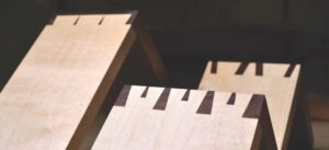 Close-up of wooden dovetail joints on workbench highlighting precision carpentry and woodworking craftsmanship.