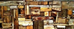 Textured wall featuring an assortment of reclaimed wood pieces in various sizes, shapes, and shades of brown and tan, creating a rustic and eco-friendly design aesthetic