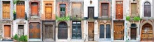 A panoramic collage of various doors in different styles and states of repair. The doors are set in buildings with distinct architectural features, showcasing a range of colors, materials, and designs from vibrant orange with intricate woodwork to weathered brown with peeling paint. Some doors have plants growing over them, while others feature ornate metalwork or simple, unadorned surfaces. This image represents the diversity in door designs and the stories they might tell about the buildings they belong to and the areas where they are found.