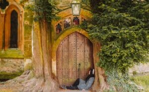 A person sitting against a large wooden door framed by two massive tree trunks, part of an old stone building with stained glass windows above, surrounded by lush greenery.