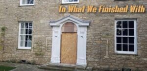 A stone building facade with three white-framed windows and a central doorway. The doorway is boarded up with plywood and has a decorative white architrave. Above the doorway, there is large text in orange that reads "To What We Finished With.